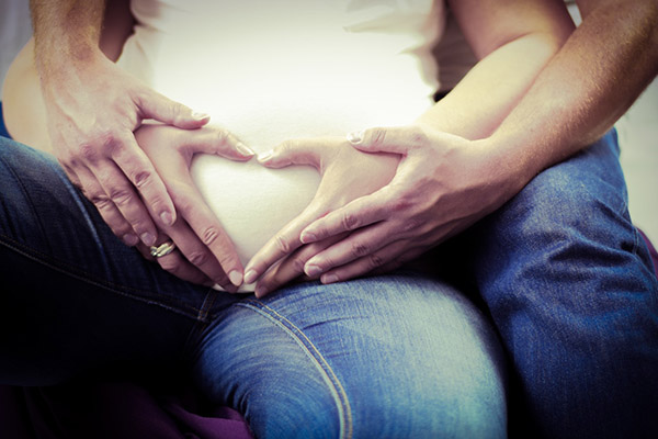 Gravid kvinna och partner håller om sin mage
