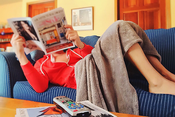Person ligger på soffa och läser en tidning